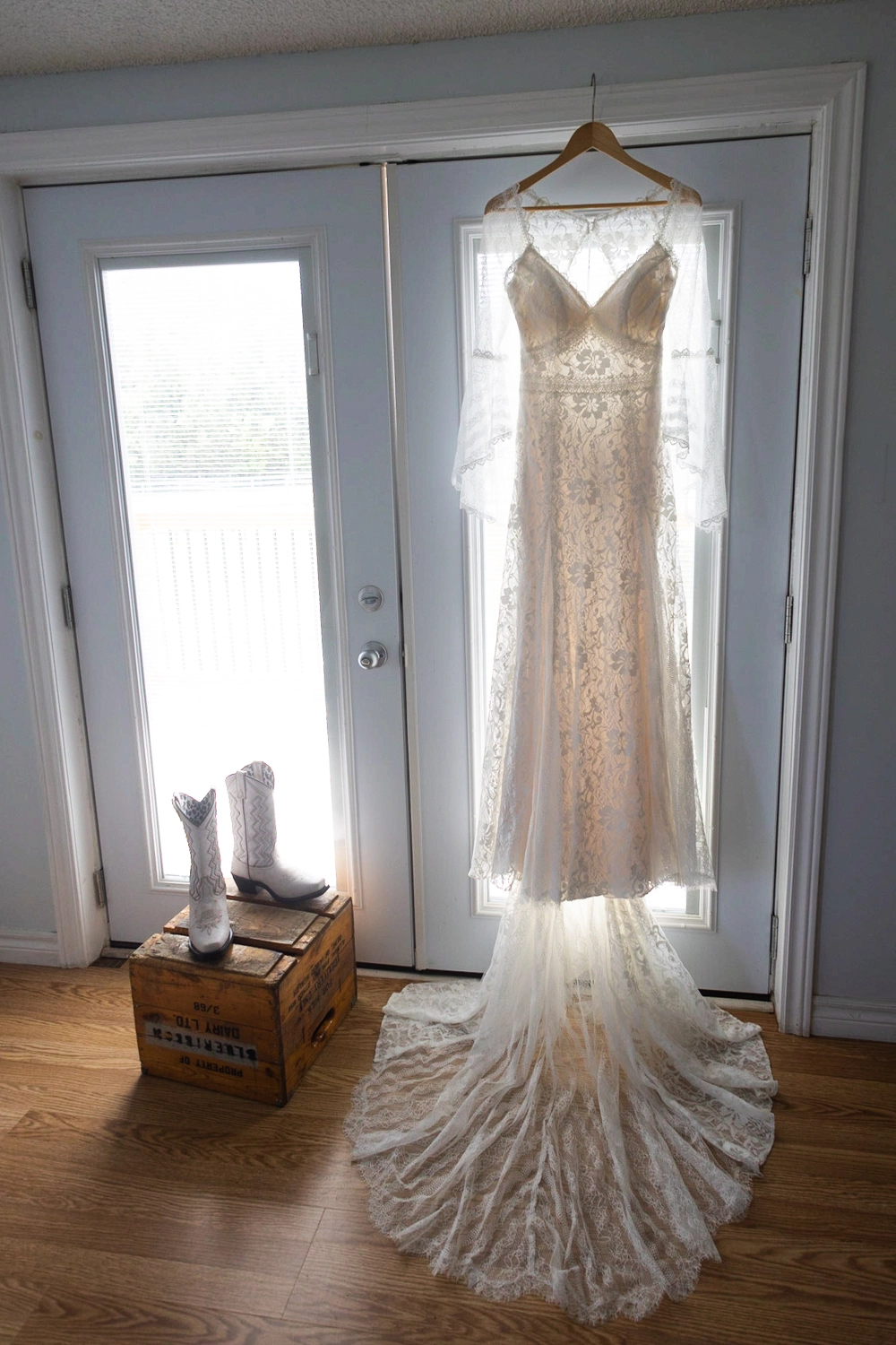 A beautiful rustic shot featuring the bride’s wedding dress paired with cowboy boots inside a charming barn, captured with a fine art Southern Ontario wedding photography style.