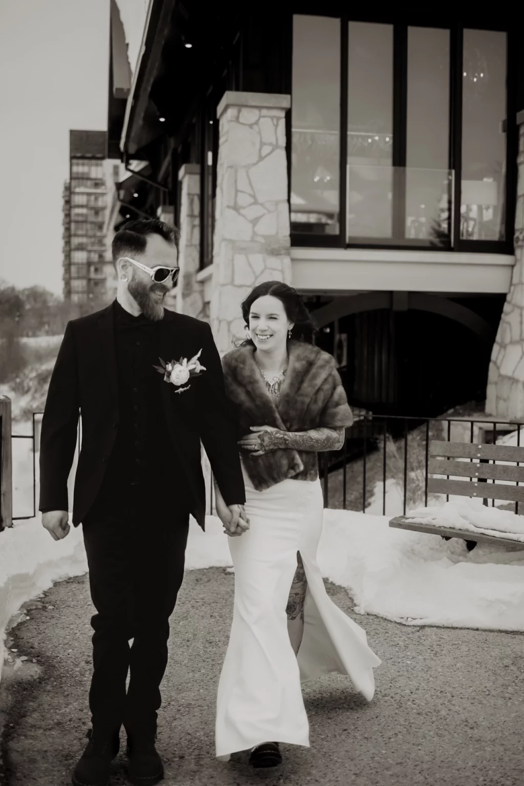Couple walking outside Cambridge Mill wedding venue in a black and white photo Title: cambridge-mill-best-wedding-locations