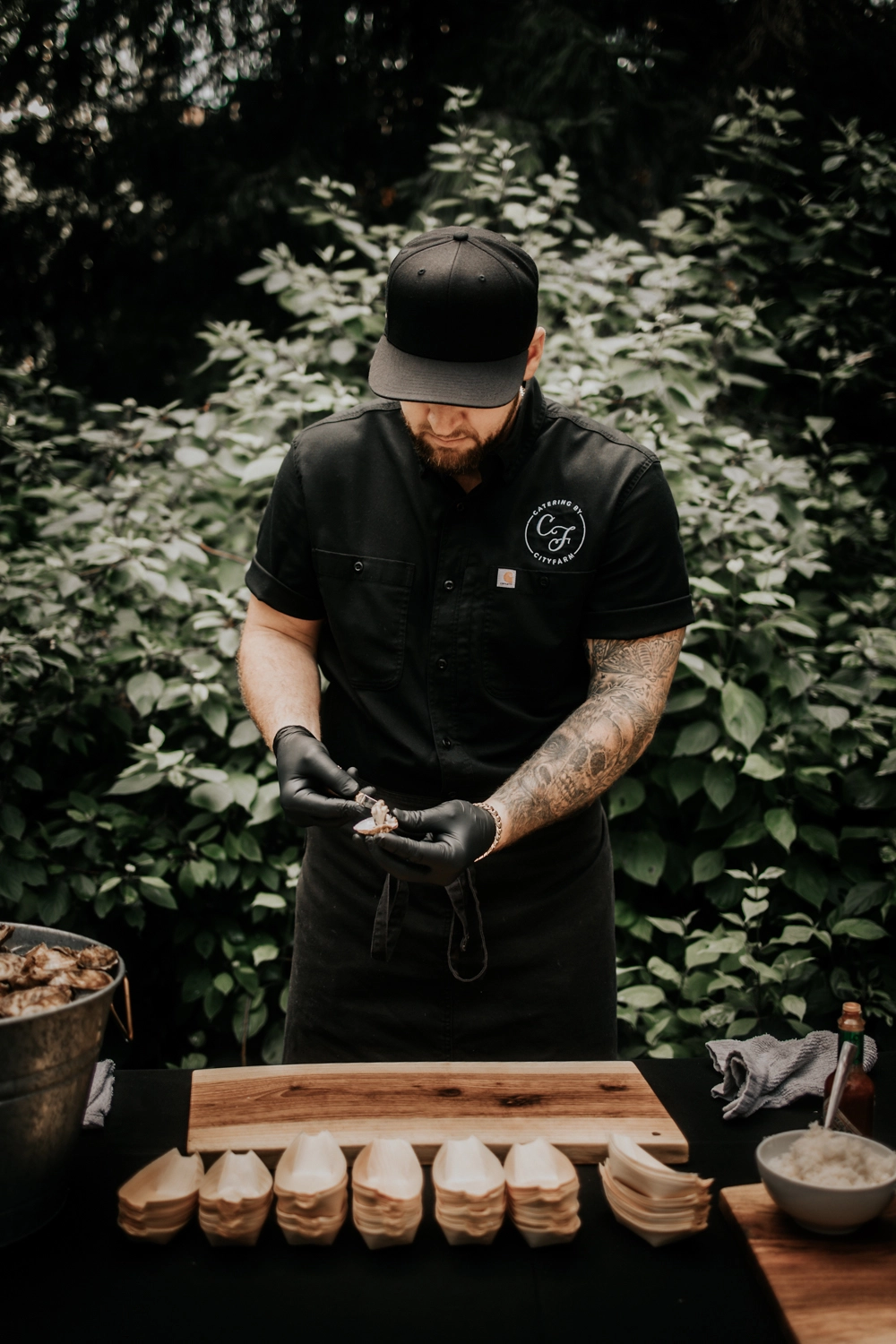 Chef expertly shaking oysters at a CityFarm Catering event, showcasing culinary skill and fresh ingredients.
