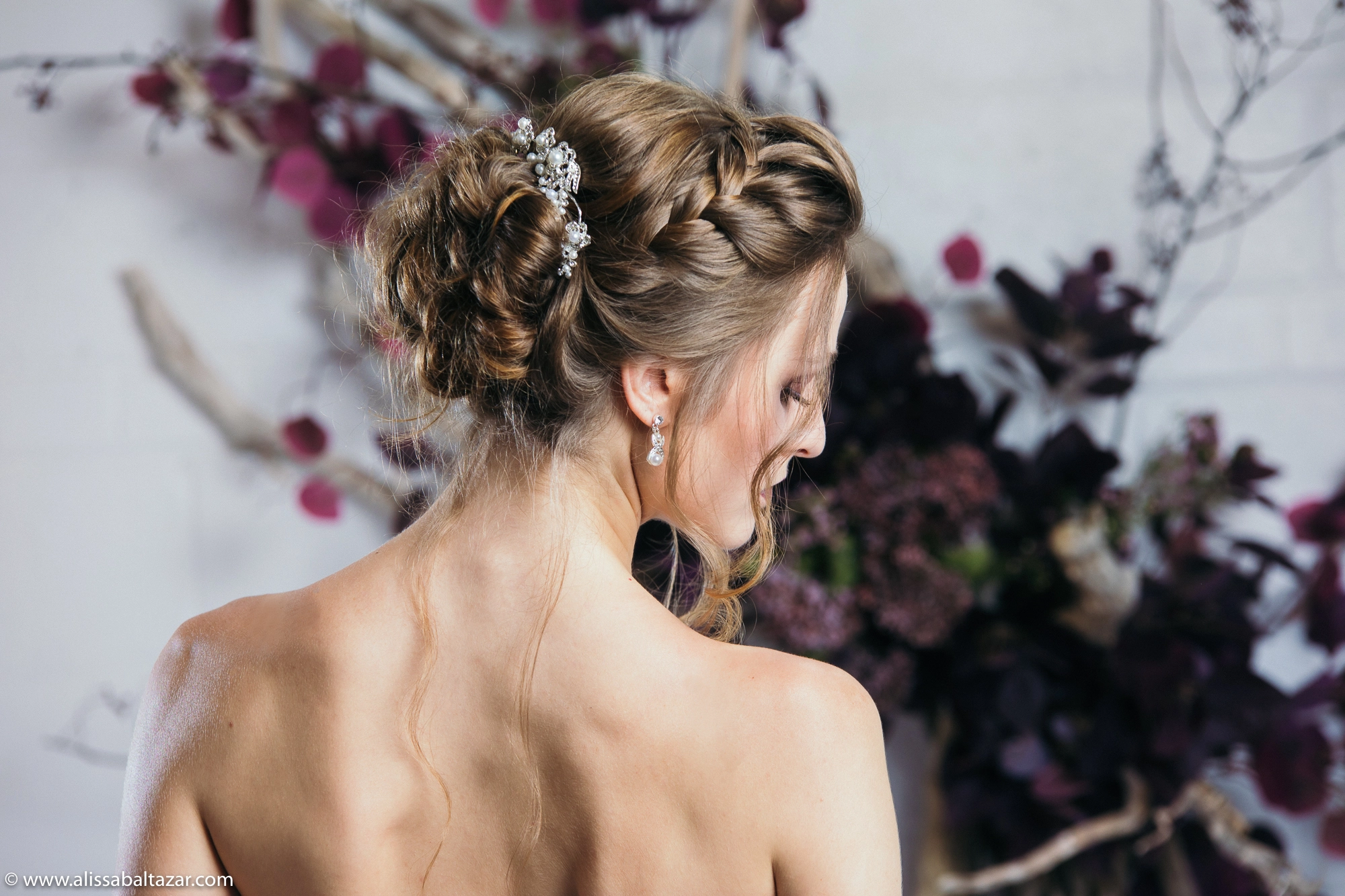 Elegant close-up profile portrait of the bride indoors, with soft floral elements in the background creating a romantic atmosphere.
