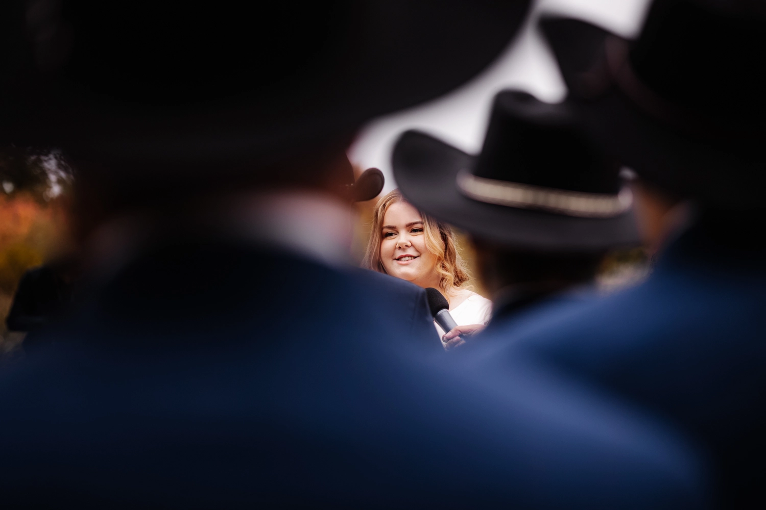 Stunning bridal portrait featuring the bride surrounded by rustic cowboy hats, capturing the spirit of a cowboy-themed wedding.