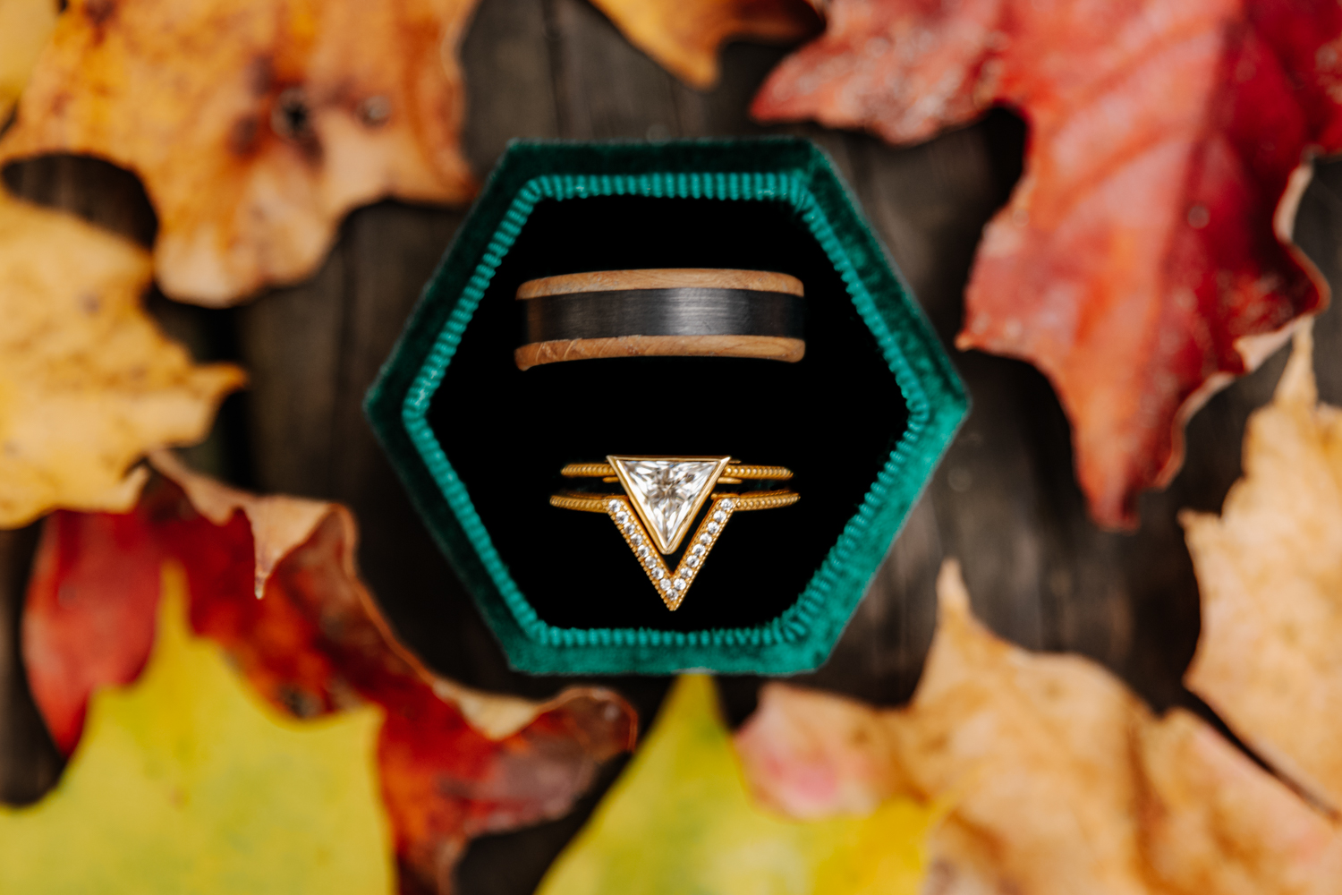 Beautiful wedding rings nestled among vibrant red fall leaves, captured in Southern Ontario wedding photography style.