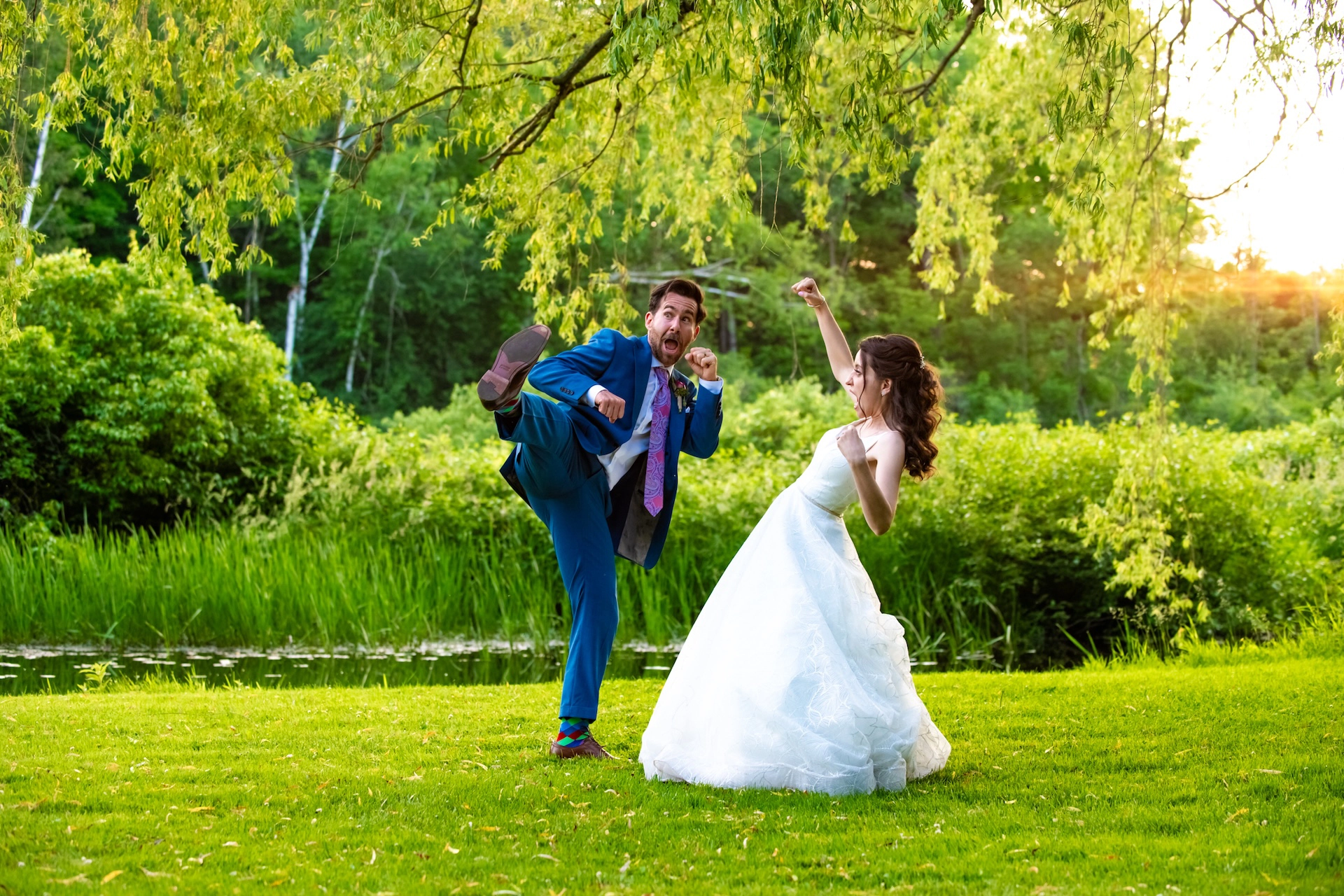 Playful wedding couple striking karate kick poses for a fun and energetic photo moment.