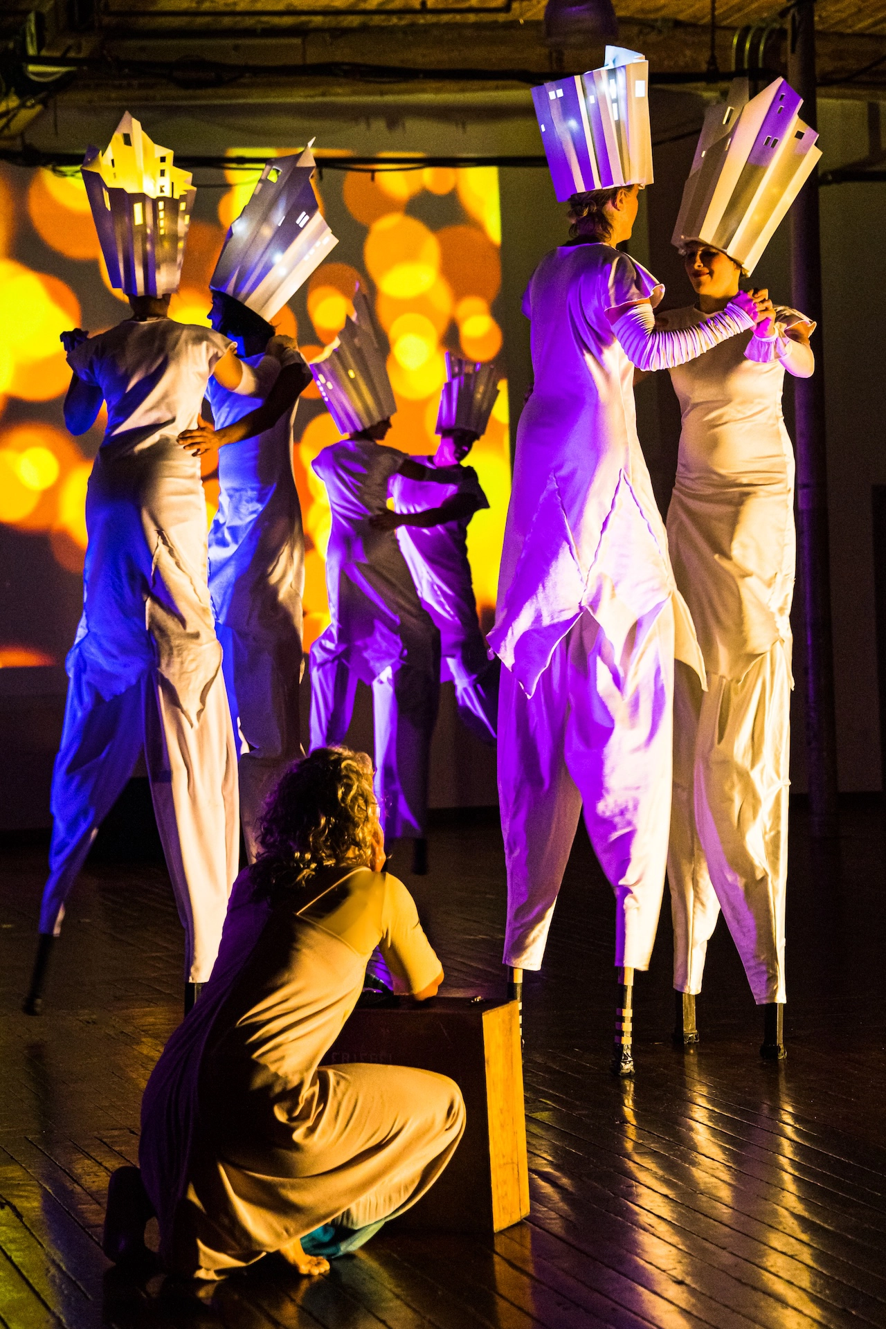 Circus performers on stilts entertain the audience at a thrilling indoor event hosted by Hamilton Aerial Group.