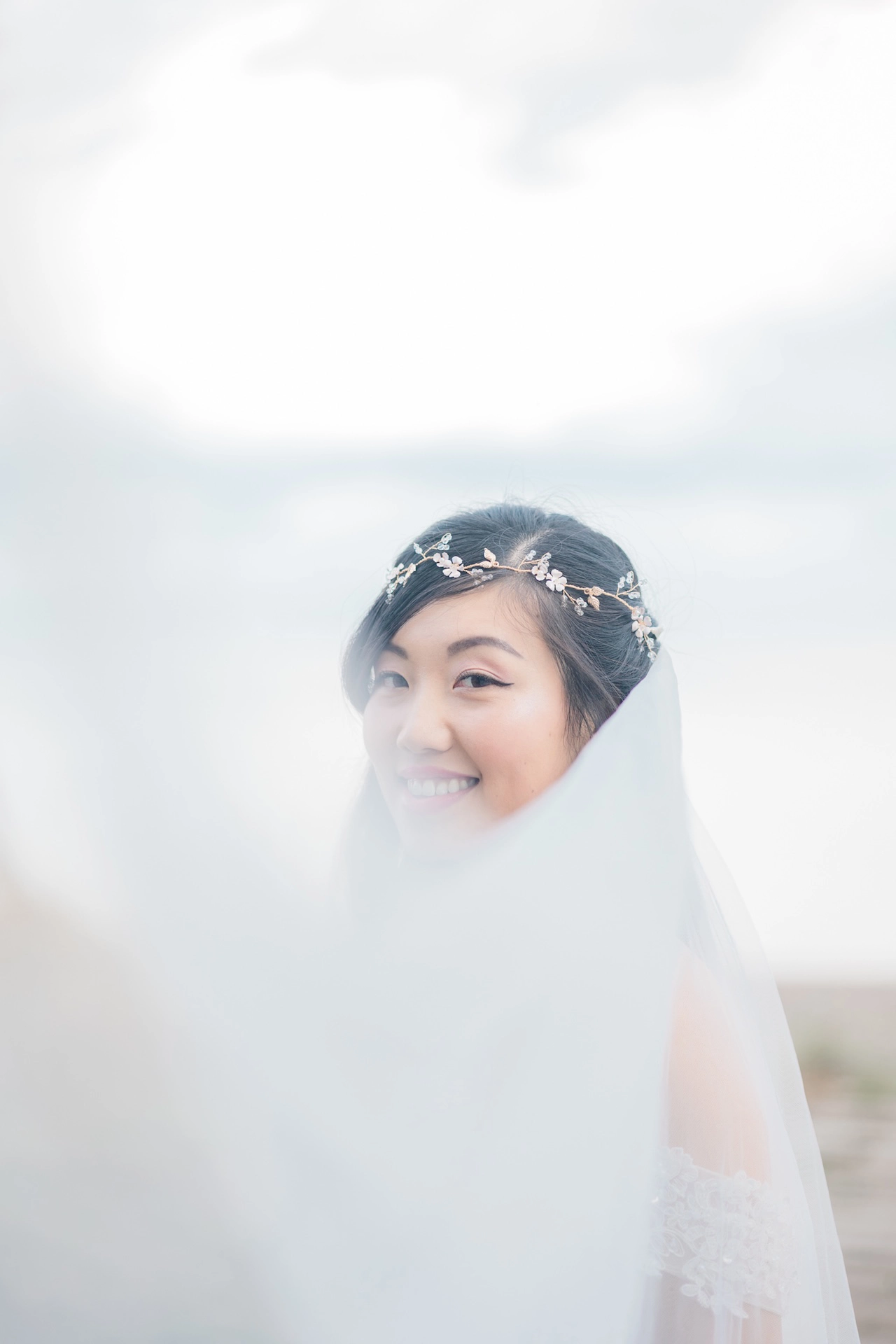 Intimate bridal portrait captured close-up through a delicate veil, evoking romance and softness.