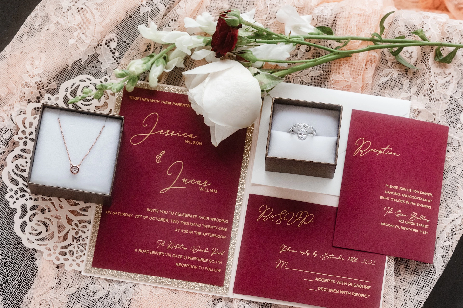A romantic flat lay of wedding invitations styled with fresh rose and sparkling jewelry.