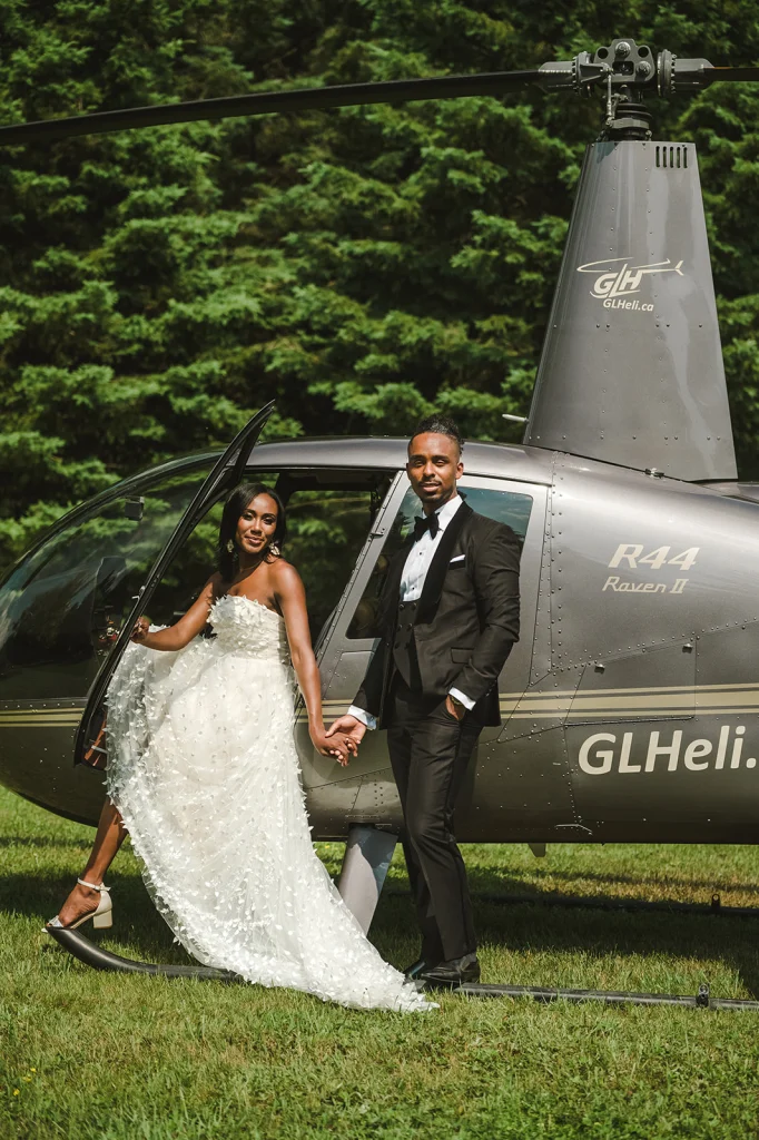 A bride and groom posing elegantly beside a helicopter, capturing the perfect blend of luxury and adventure on their wedding day.