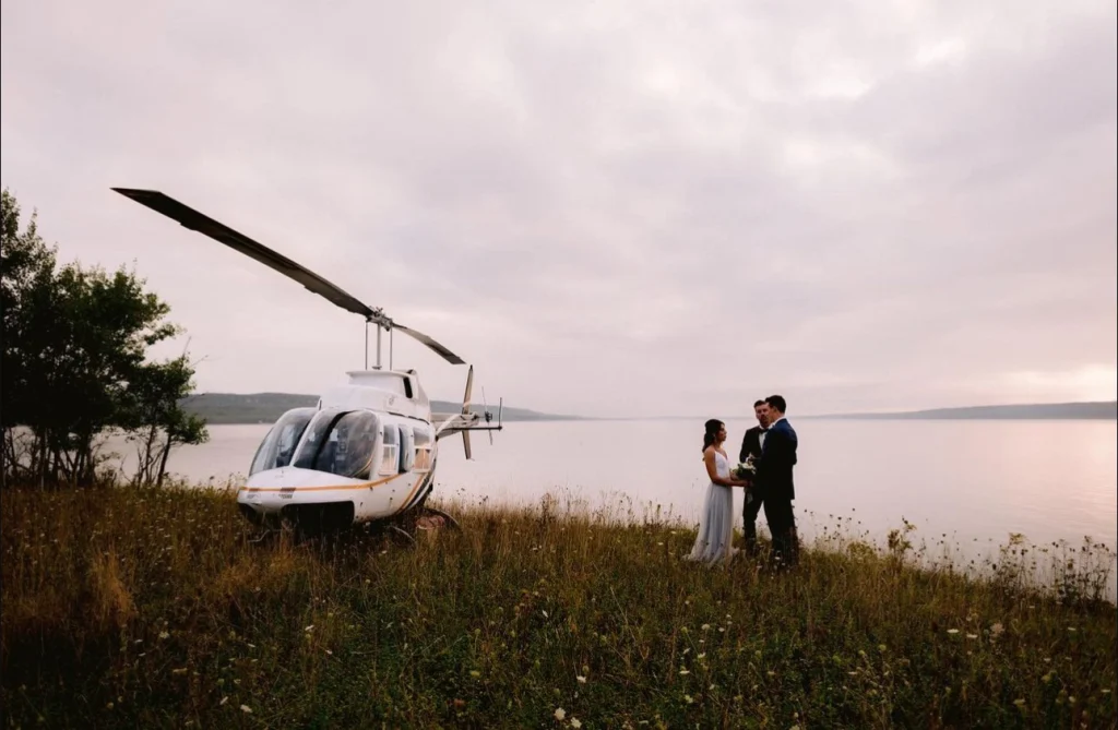 Bride and groom standing beside a helicopter, ready for a stylish and adventurous wedding entrance.