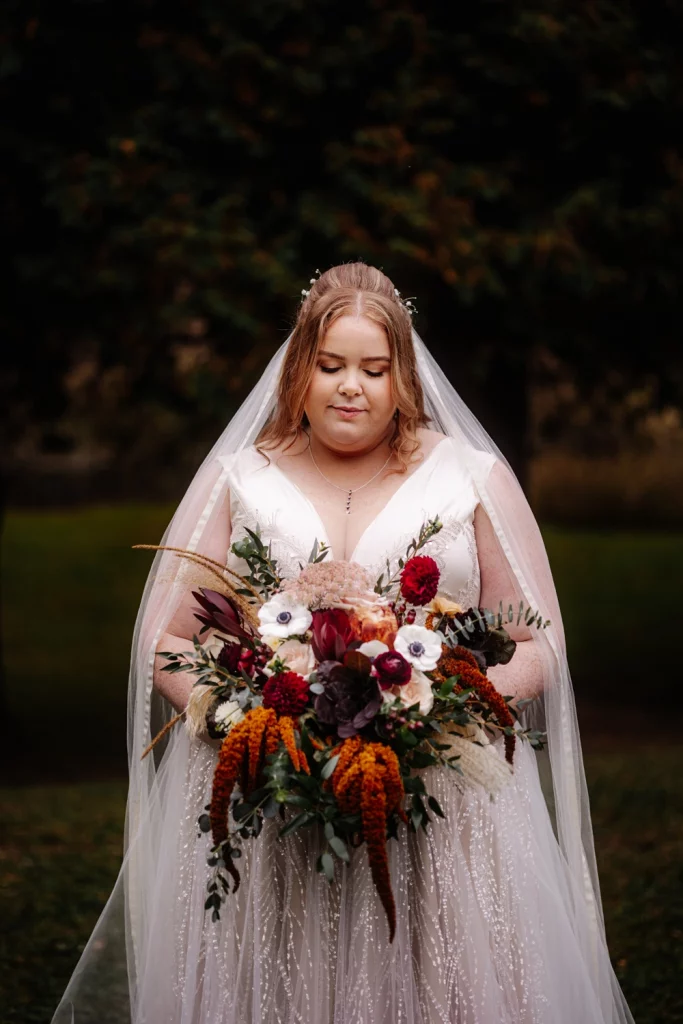 Stunning fall bride portrait looking down on her bouquet.