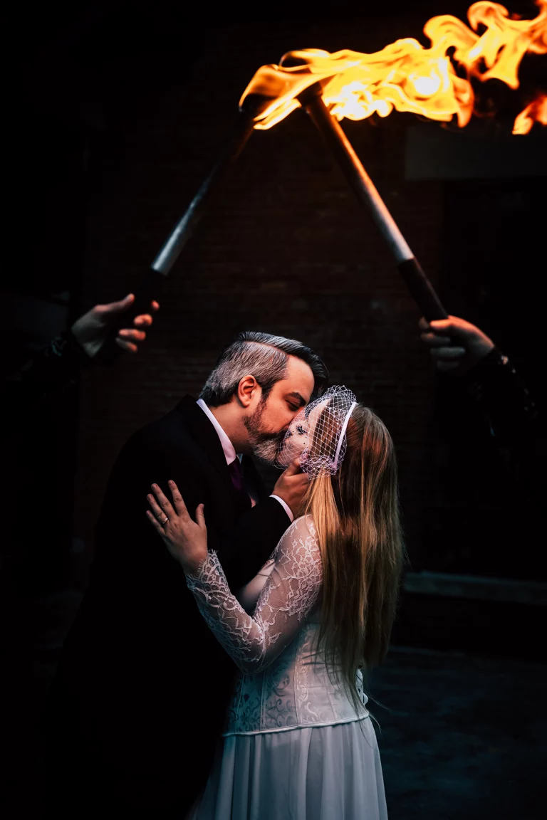 Duo fire dancers striking a dramatic pose with flames, showcasing unique wedding entertainment for the reception and framing bride and groom.