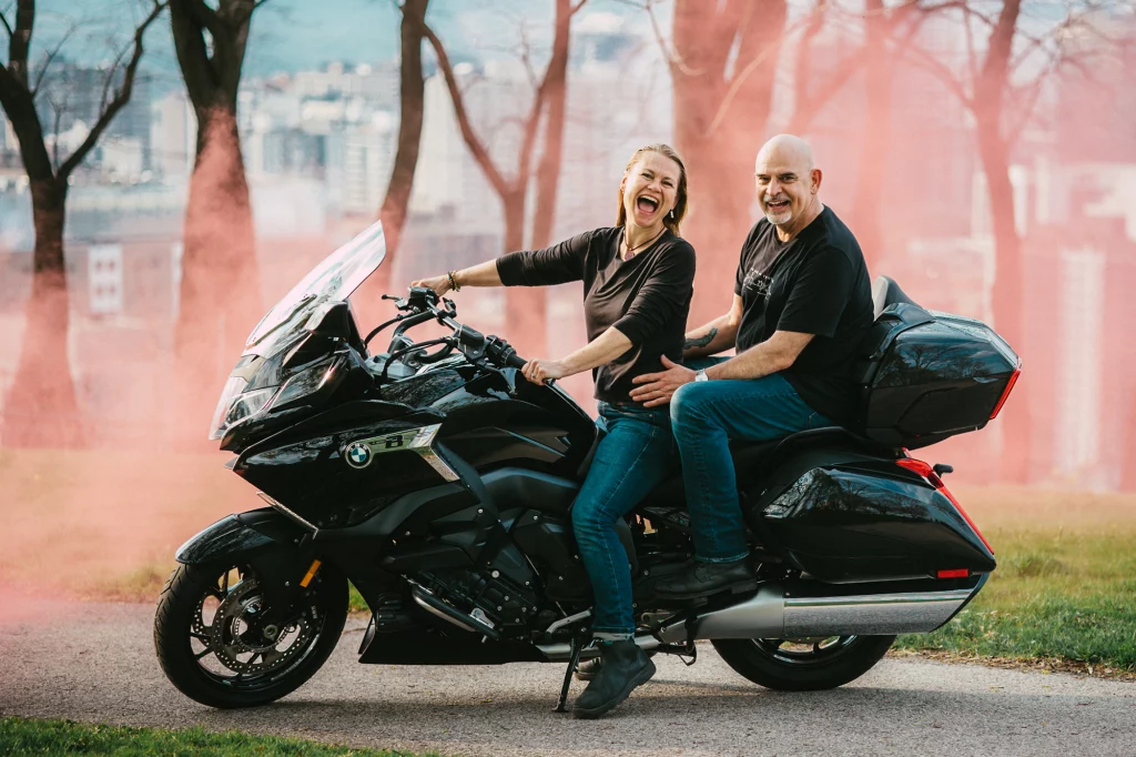 Happy couple laphing on motocicle serounded be red fog.
