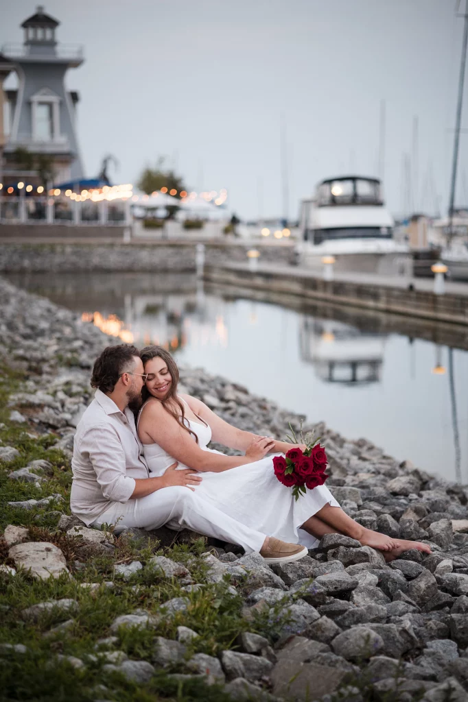 Couple wearling white sitting next to the watter at the yacht club.
