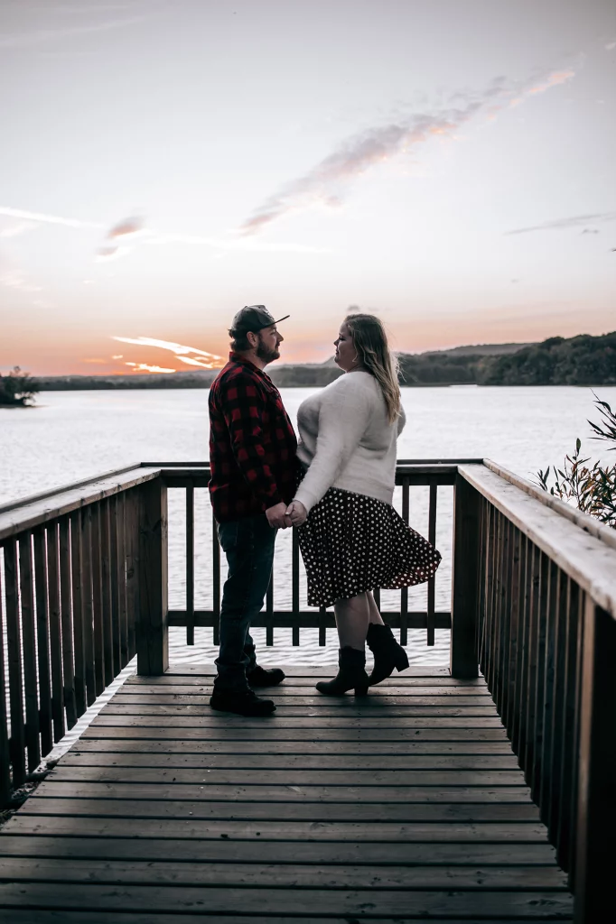 Engagement photos of Madelaine and Nicholas at Princess Point during a golden fall sunset surrounded by forest and waterfront views.