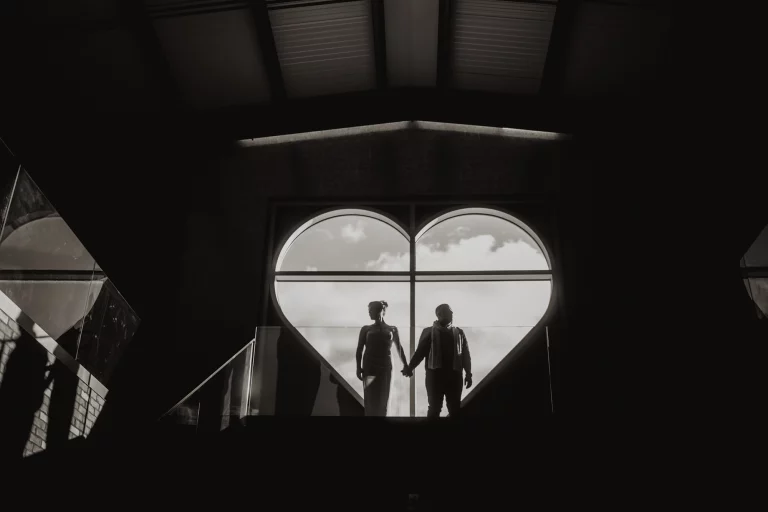 Couple holding hands in heart-shaped window at AMO Estate Winery – photoshoot locations in Southern Ontario